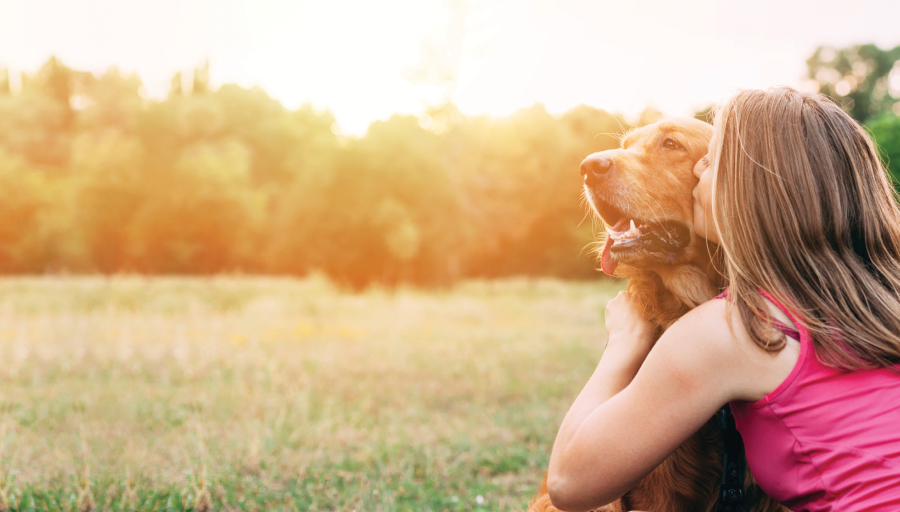 Žena je sjedila sa svojim psom vani u polju i ljubila mu lice